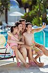 Family with two children taking selfie by swimming pool