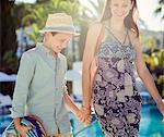 Mother and son holding hands by swimming pool