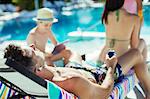 Family with two children sunbathing by resort swimming pool