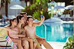 Family with two children taking selfie by swimming pool