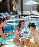 Family with two children splashing water in resort swimming pool