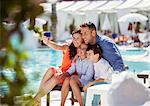 Family with two children taking selfie by resort swimming pool