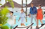 Family with two children walking together by swimming pool