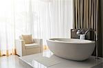 View of modern and luxurious bathroom with bathtub and armchair