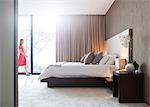 Woman in red dress walking through modern bedroom