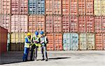 Worker and businessmen talking near cargo containers