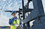 Worker using walkie-talkie under cargo crane