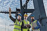 Businessmen and worker talking near cargo crane