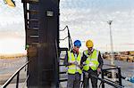 Workers using walkie-talkie on cargo crane