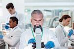 Scientist examining sample under microscope in laboratory