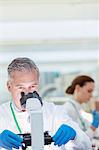 Scientist examining sample under microscope in laboratory