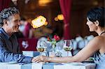 Mature couple sitting face to face and holding hands at restaurant table
