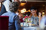 Mature couple in restaurant, waiter pouring white wine