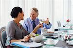 Smiling mature couple raising toast with white wine at restaurant table