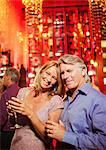 Portrait of smiling mature couple in bar, man in background