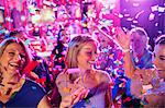 Confetti falling on smiling mature women dancing in nightclub