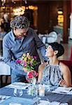 Man giving bouquet of flowers to woman in restaurant