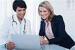 Doctor and patient using laptop in hospital office