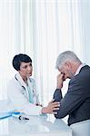 Female doctor sitting at desk and consoling sad patient