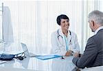 Smiling female doctor talking to patient at desk in office