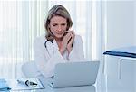 Female doctor sitting at desk with laptop in office