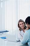 Female doctor talking to woman at desk in office