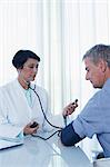 Female doctor taking patient's blood pressure at desk in office