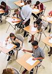 Overhead view of students passing note between desks during their GCSE exam