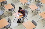 Elevated view of lone female student writing their GCSE exam in classroom