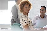 Portrait of businesswoman in office, colleagues in background