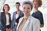 Portrait of smiling mature businesswoman with office team in background