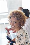 Portrait of smiling young woman in office, colleagues in background