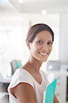 Portrait of smiling businesswoman holding documents in office