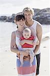 A family day out on the beach. Two people and a baby.