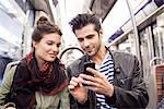 Friends riding subway looking at smartphone together