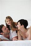 Parents and daughter lying on bed together, portrait