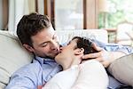 Couple relaxing together on sofa, preparing to kiss