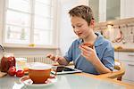 Boy playing with digital tablet at breakfast table
