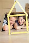 Couple inside cardboard box ruler house shape