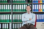 Man sitting chair filing cabinet office relaxed