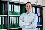 Businessman standing filing cabinet office relaxed