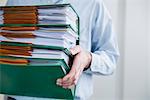 Close up man carrying pile filing folders