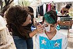 Female makeup artist putting makeup on male clown