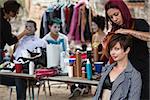 Makeup artist with red hair fixing young woman's hairdo