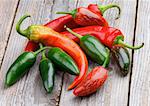 Arrangement of Red and Green Habanero and Jalapeño Chili Peppers isolated on Rustic Wooden background