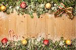 Christmas background with firtree, candies and baubles with snow and stars on wood