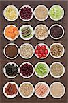 Large diet health food selection in porcelain bowls over lokta paper background. With titles.