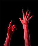 Red spooky devil hands with black nails, Halloween theme, isolated on black background