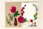 Love potion ingredients over natural hemp notebook and mottled cream paper background.
