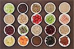 Large diet health food selection in porcelain bowls over lokta paper background.